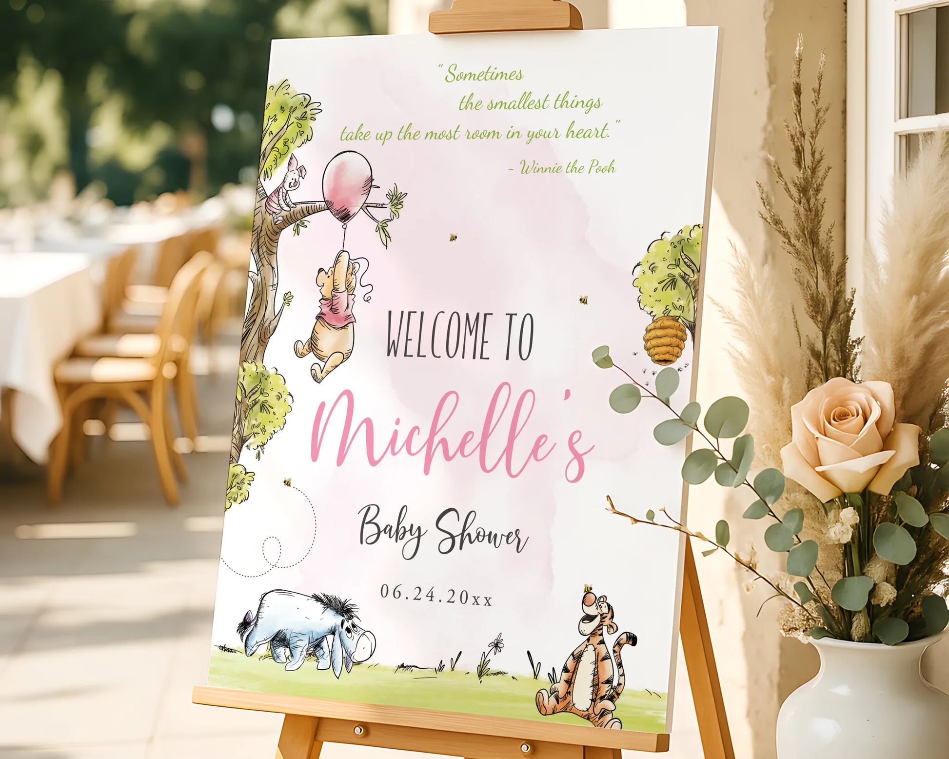 Personalized Winnie the Pooh baby shower welcome sign displayed on a wooden easel with flowers