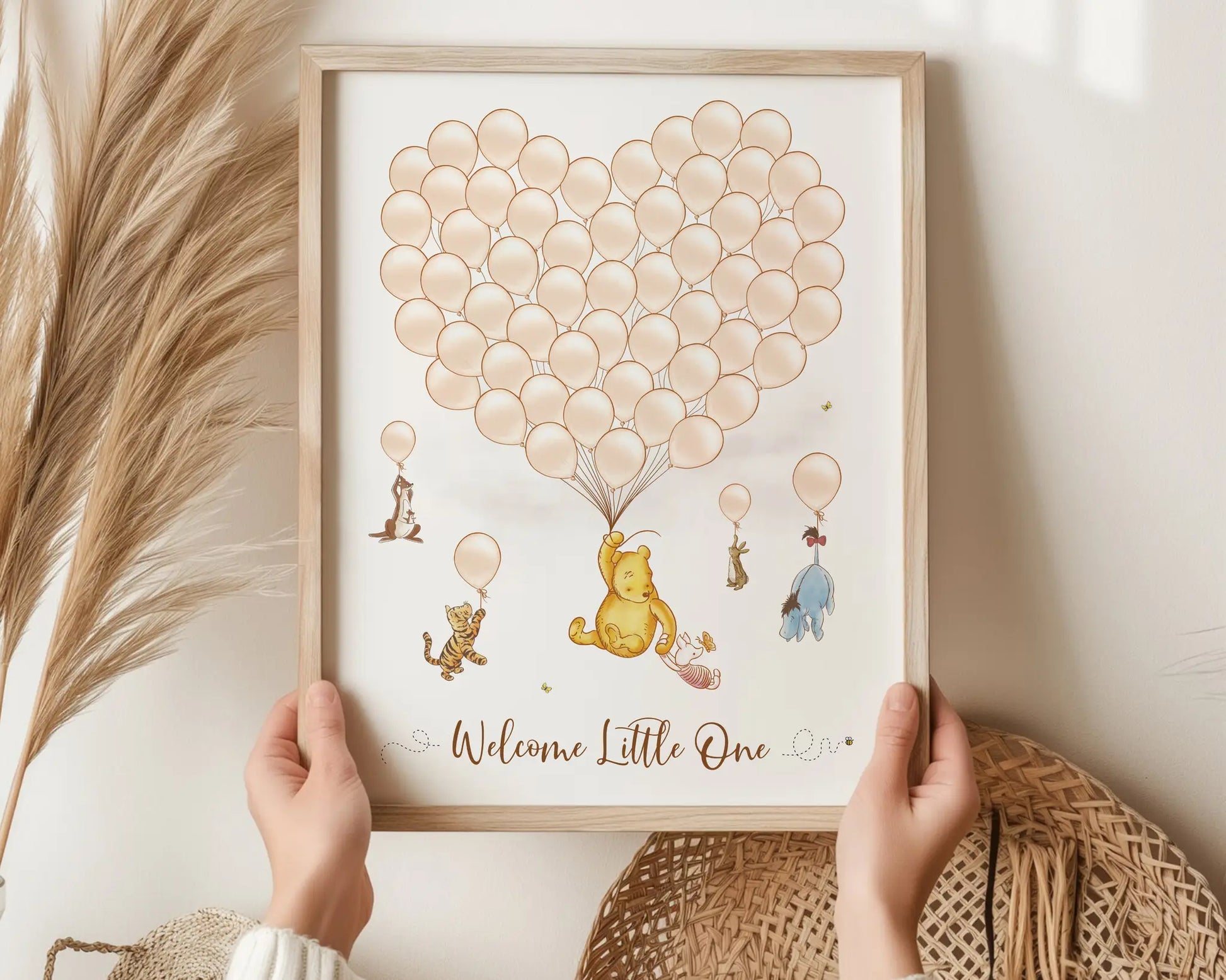 Winnie the Pooh baby shower guest book in beige tones with heart balloon cluster and Pooh characters, held by hands in natural boho setting.