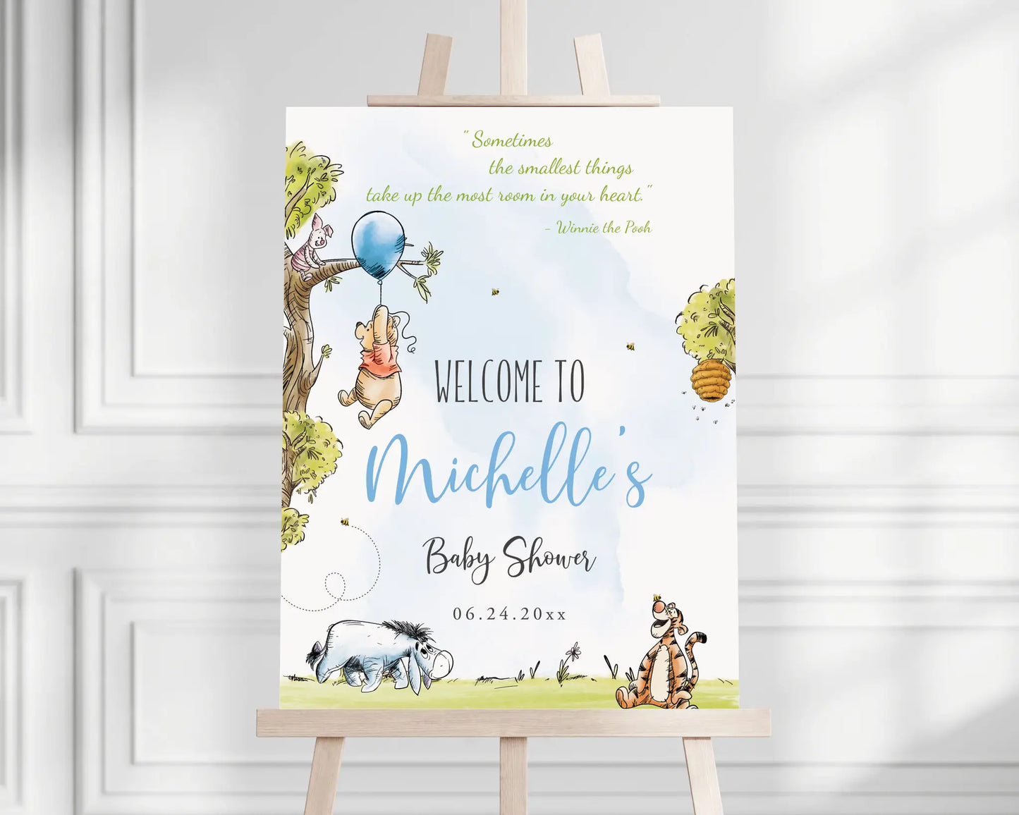 Winnie the Pooh baby shower welcome sign with blue balloon and woodland tree displayed on an easel, printable Canva template.