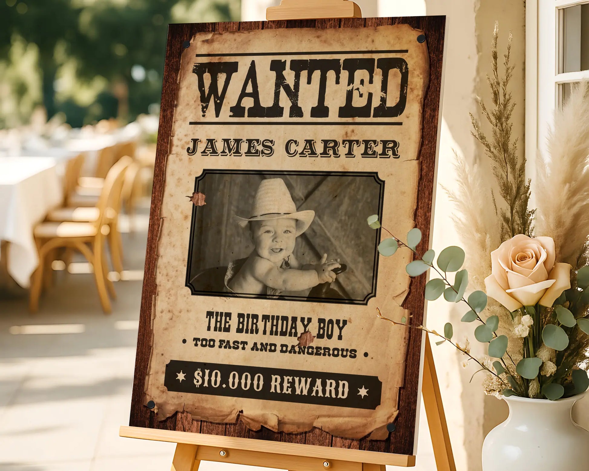Rustic western birthday photo prop featuring customizable Wanted Poster design with photo, displayed outdoors with warm natural light.